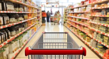 Shopping trolley, empty, with red handle on blur supermarket ais