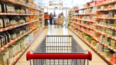 Shopping trolley, empty, with red handle on blur supermarket ais